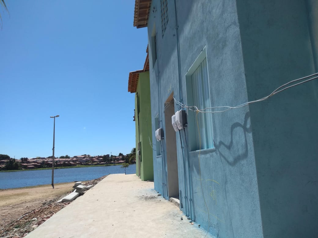 duas casas lado a lado vistas de perfil com lagoa do urubu ao fundo